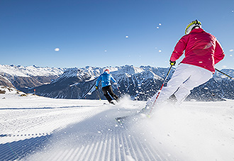 2 Personen fahren mit Skier eine Skipiste herunter